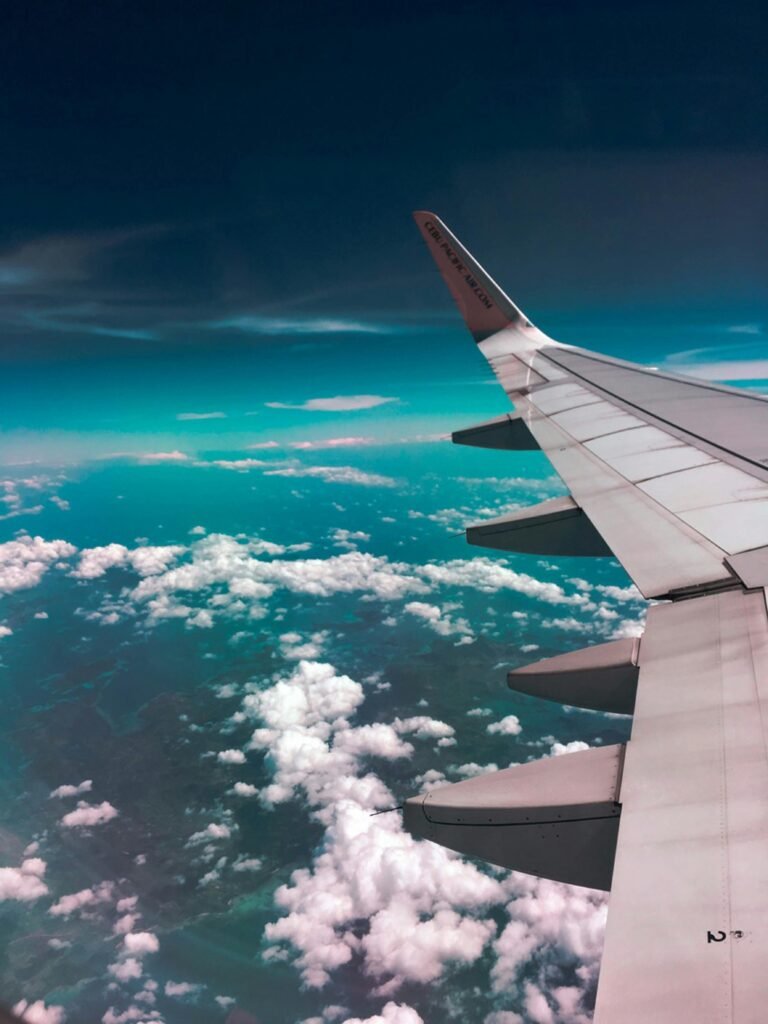 pexels-photo-731217-731217-1 Aerial view of airplane wing over fluffy clouds with a deep turquoise sky.