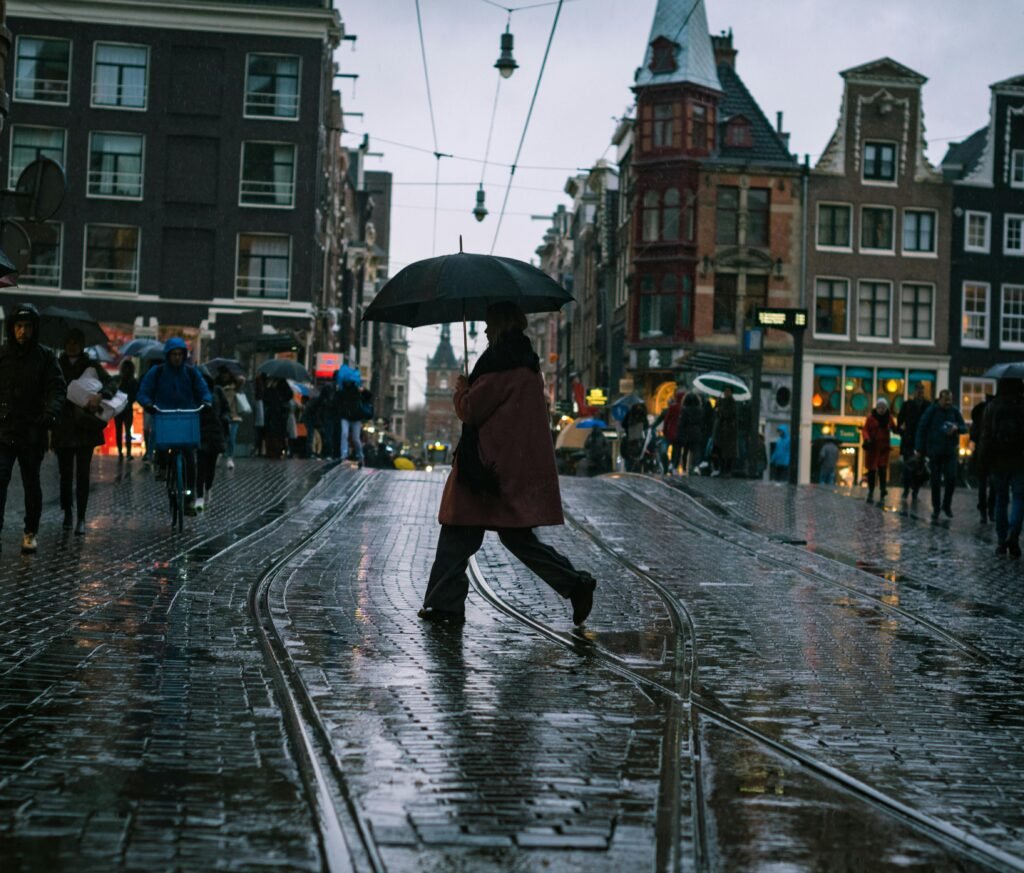 pexels-photo-10914617-10914617 A person walks with an umbrella on a rainy day in Amsterdam's historic streets.