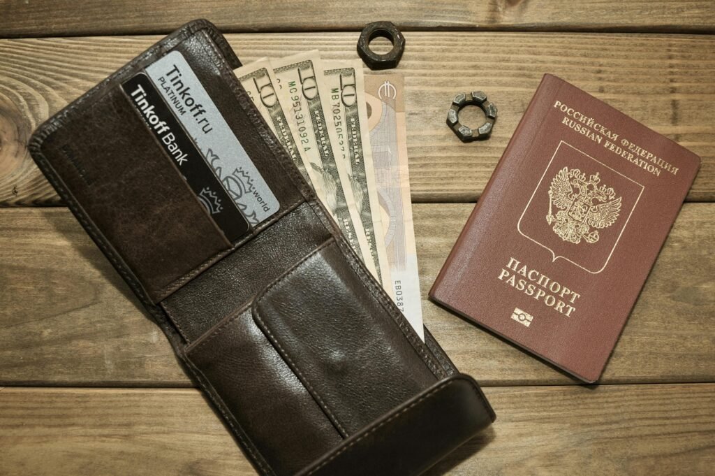 pexels-photo-4430246-4430246 Brown leather wallet with cards, assorted currencies, and passport on wood surface.