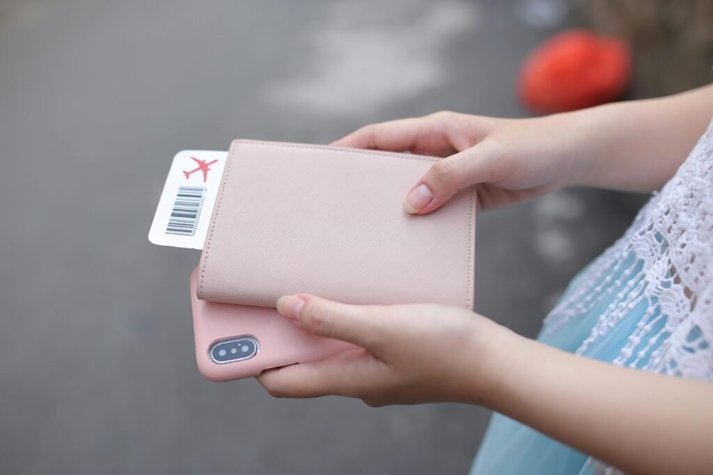 pexels-photo-5147224-5147224 A woman holding a passport with a boarding pass and a smartphone, ready for travel.