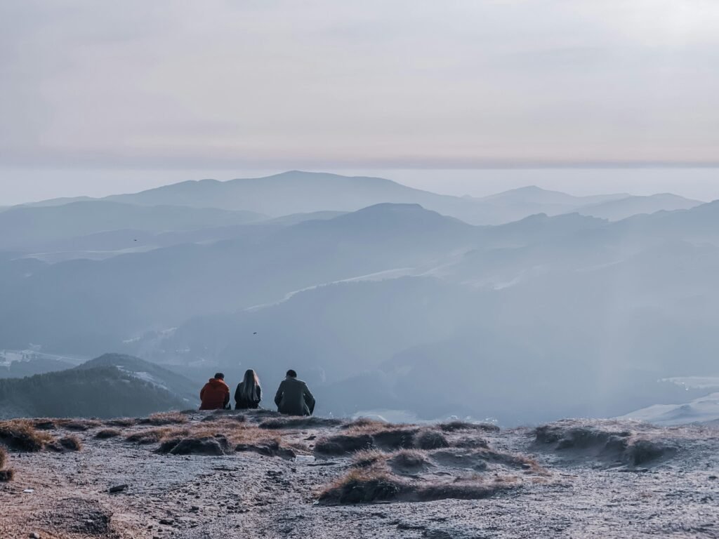 pexels-photo-5499532-5499532 Back view of anonymous group of tourists admiring mounts near lake under cloudy sky at sundown