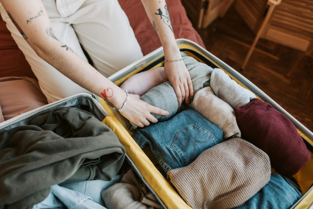pexels-photo-7368218-7368218 Close-up of a person packing various clothing items into a suitcase, ready for travel.