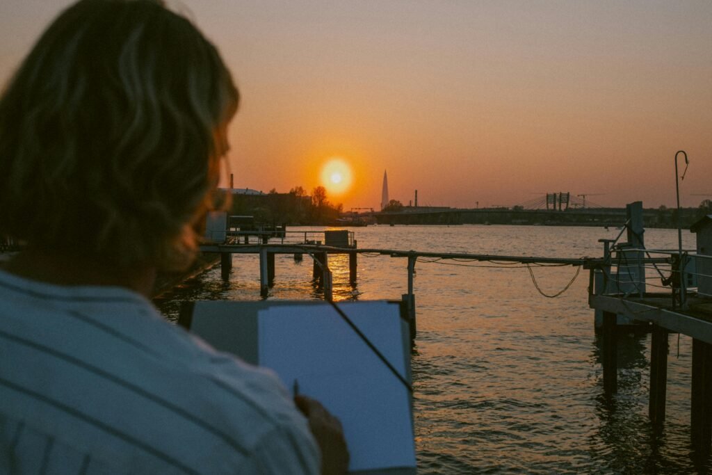 pexels-photo-9626351-9626351 Artist captures vibrant sunset by the pier, reflecting on calm waters.