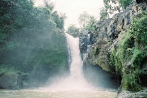 Beautiful waterfall cascading down rocky cliffs surrounded by lush greenery in Bali, Indonesia.