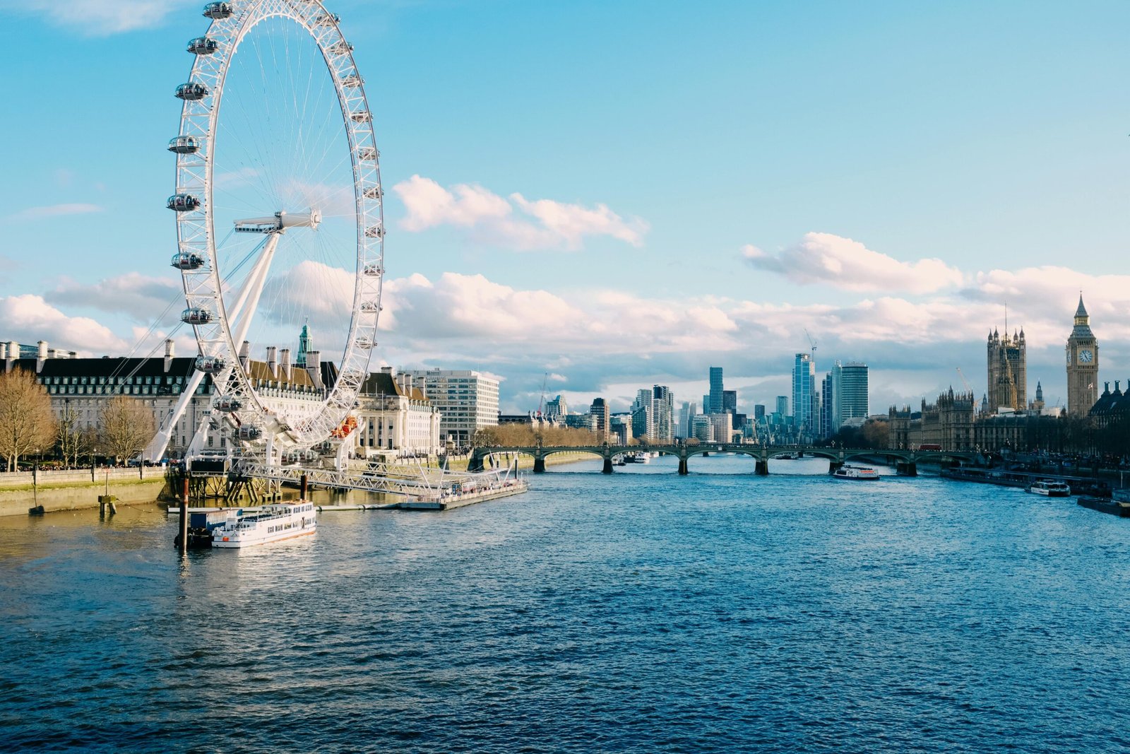 pexels-photo-16230720-16230720 Stunning view of London Eye and Thames River against bright blue sky, capturing iconic London landmarks.
