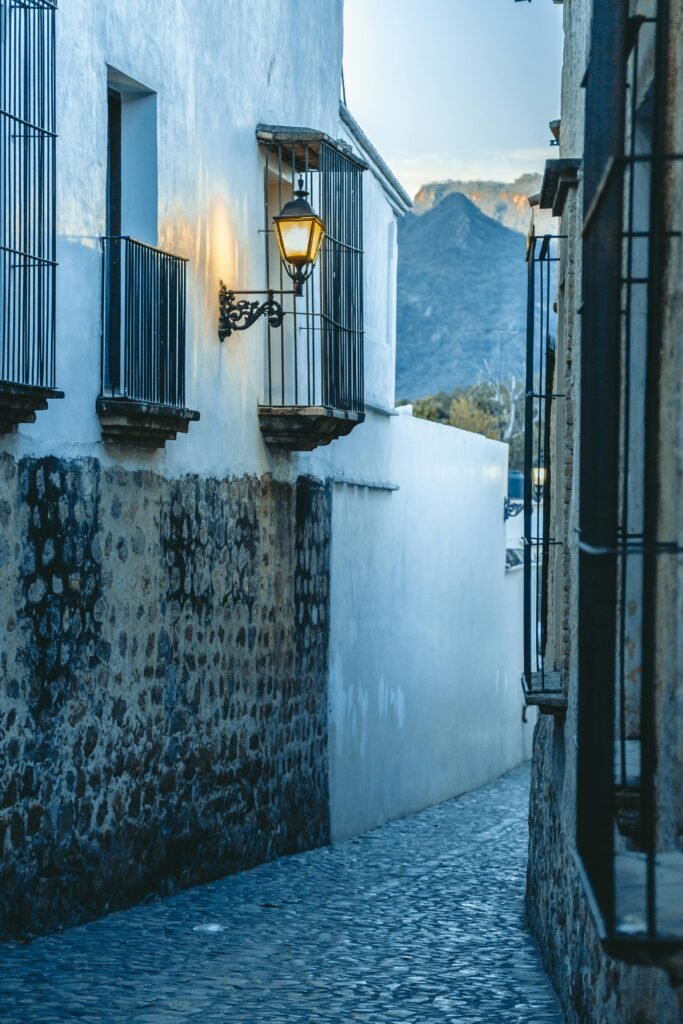 Explore a picturesque Mexican alley with cobblestone streets and rustic architecture, beautifully lit at dusk.