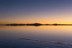 Breathtaking sunrise over the mirror-like Uyuni Salt Flats in Bolivia. A serene and tranquil landscape.