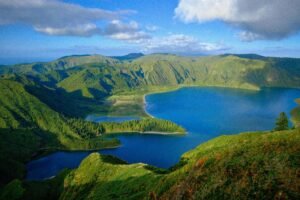 Explore the serene beauty of a lush green landscape with a tranquil lake on São Miguel Island.