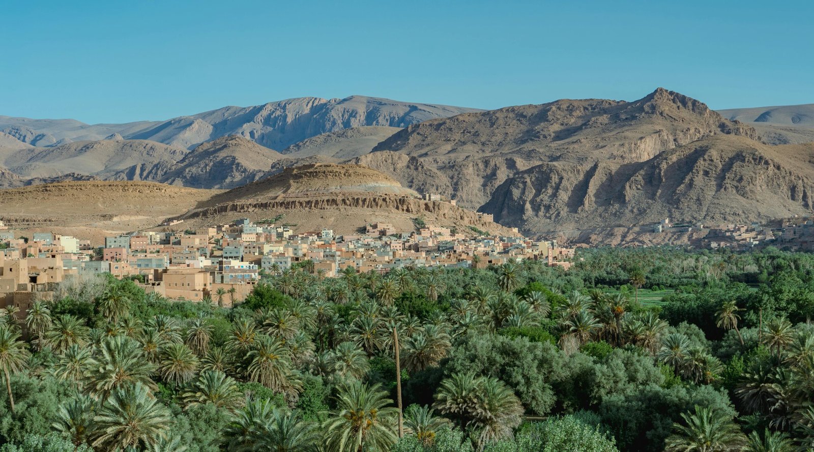 pexels-photo-30320620-30320620-1 Scenic view of Tinghir oasis with lush greenery and Atlas Mountains in the background, Morocco.