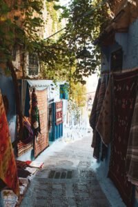 Picturesque narrow alley with vibrant rugs in the blue city of Chefchaouen, Morocco.