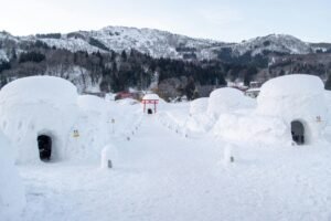 Traditional kamakura igloos in Iiyama, Nagano under a snowy landscape.