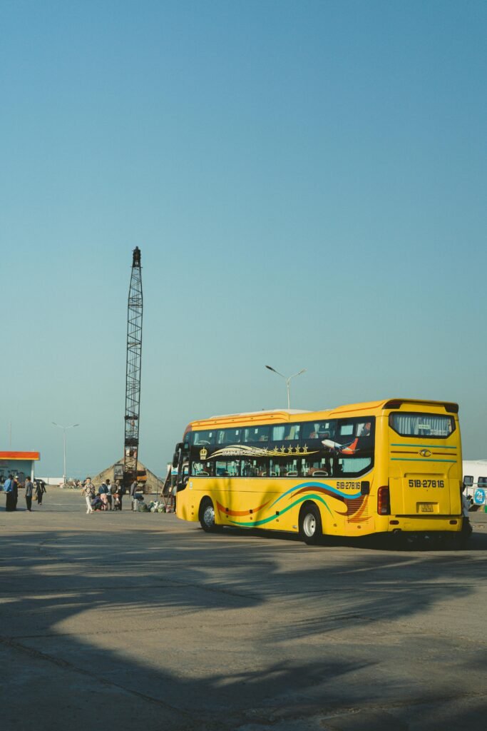 Bright yellow bus parked by the roadside in Bình Thuận, Vietnam on a sunny day.