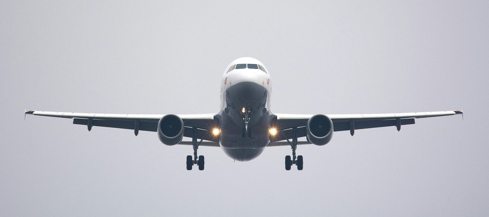 pexels-photo-358319-358319 A commercial airliner captured head-on, preparing to land against a cloudy sky.