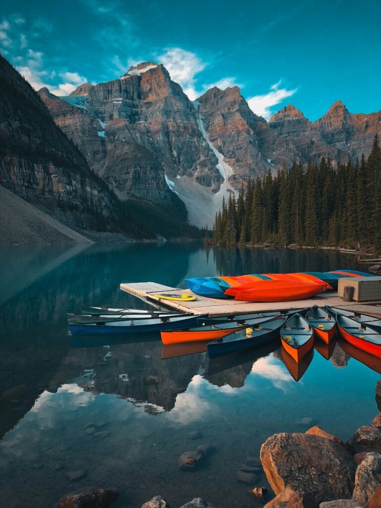 Colorful canoes on Moraine Lake with picturesque mountains reflected in the water at Banff National Park.