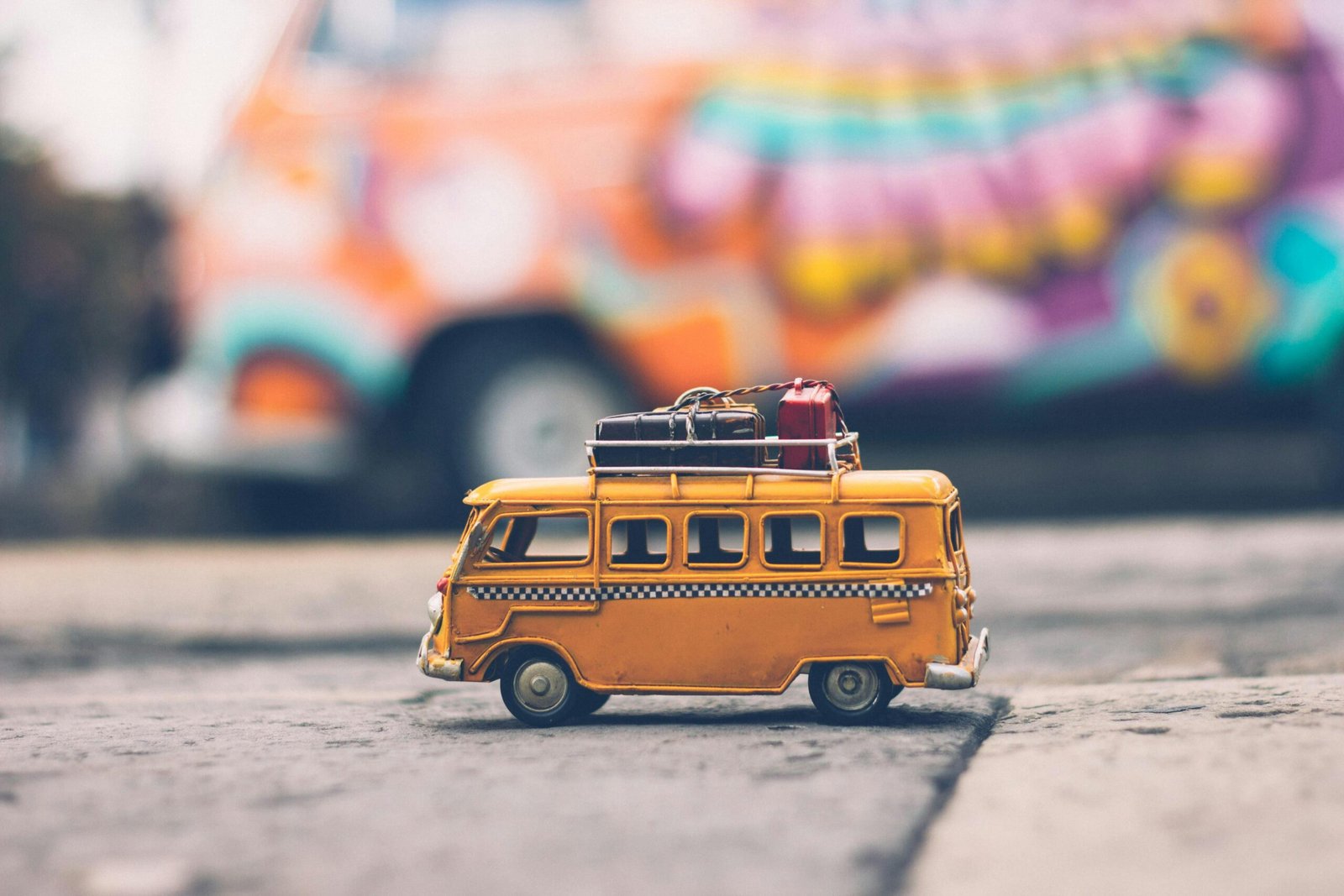 pexels-photo-386009-386009 Close-up of a toy Volkswagen van with luggage, set against a colorful street backdrop, evoking summer travel vibes.