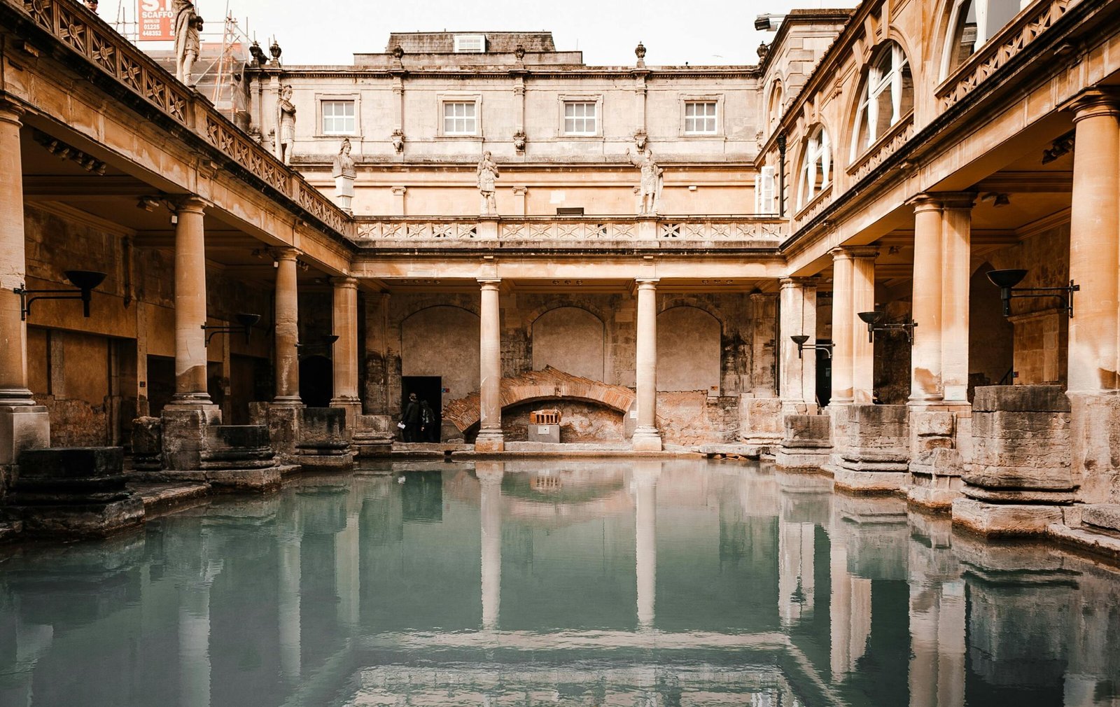 pexels-photo-4577640-4577640 Exterior of worn out medieval stone building with columns located near canal with reflection on water surface in old city
