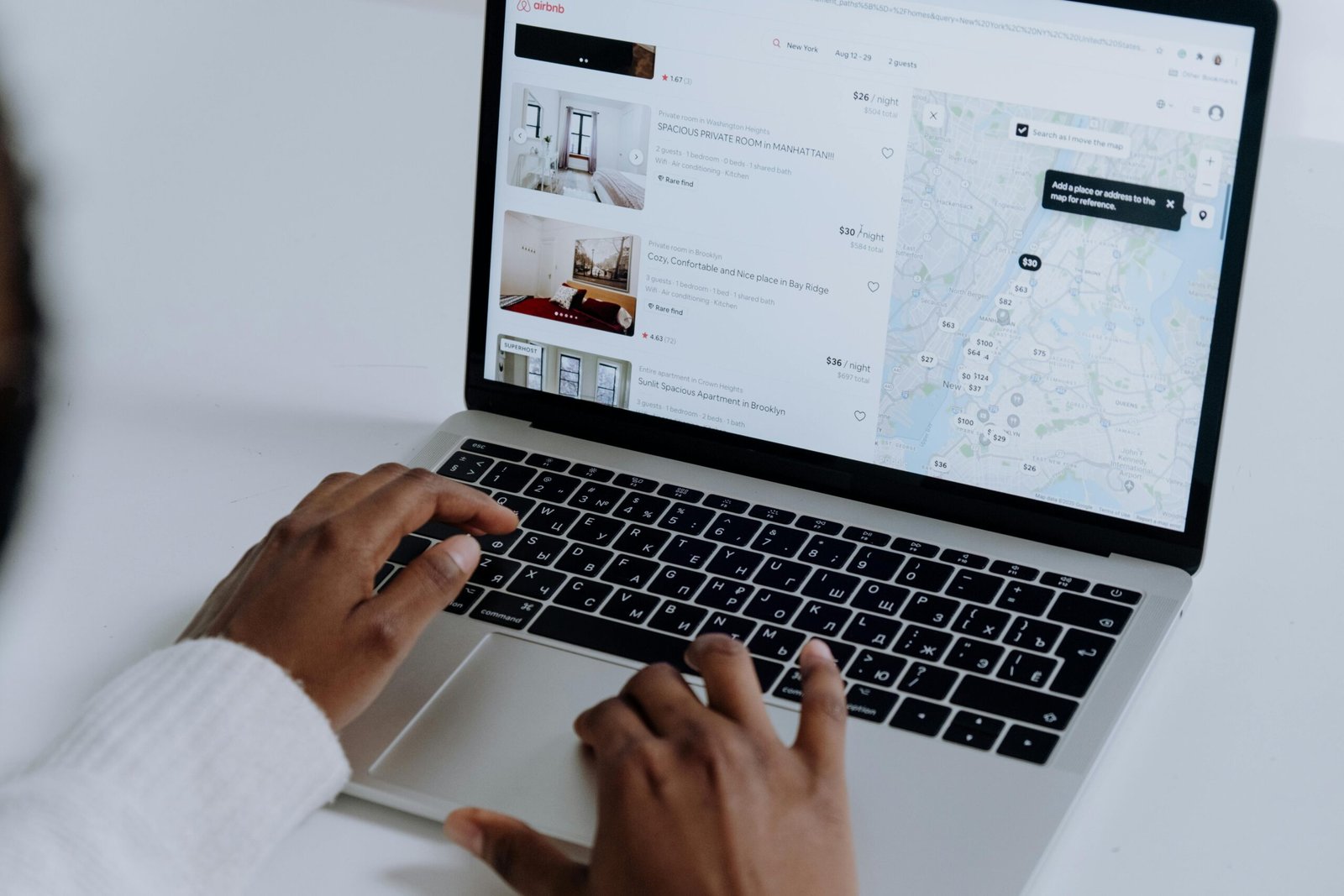 pexels-photo-5077049-5077049 Hands typing on laptop searching Airbnb for accommodation options with map view.
