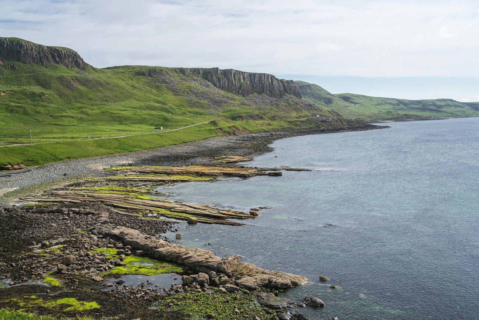 pexels-photo-6726718-6726718 Breathtaking coastal scene with lush green cliffs and serene seashore curves.