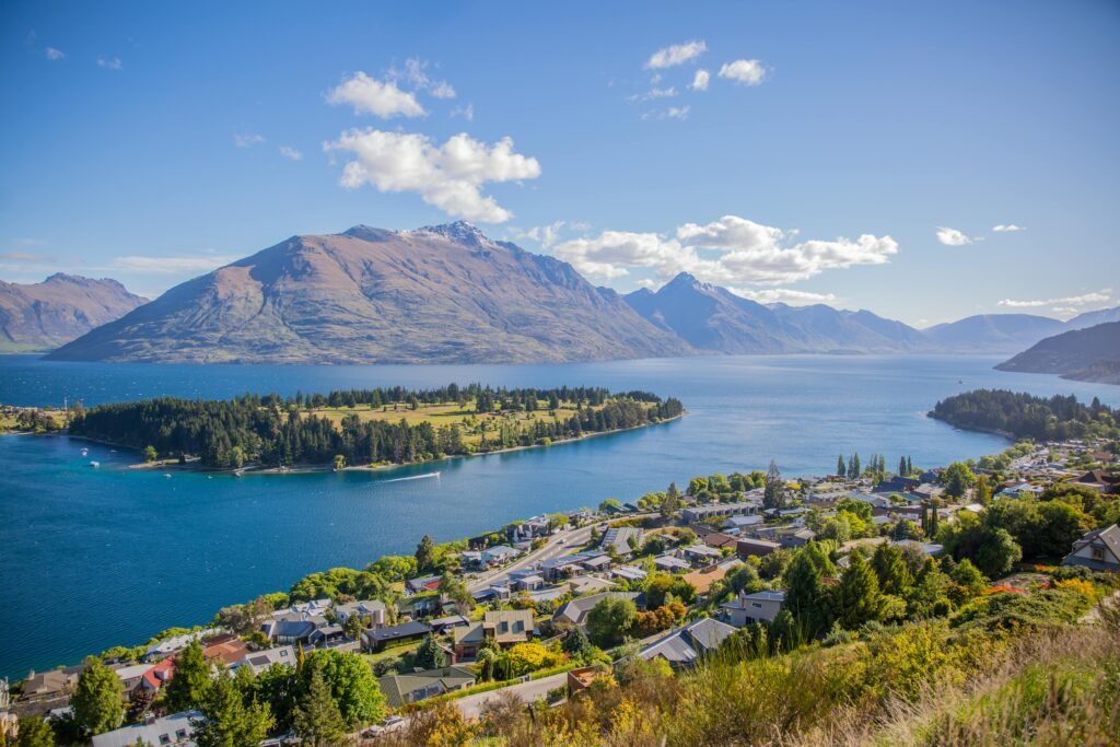 Breathtaking aerial view of Queenstown by Lake Wakatipu, surrounded by majestic mountains under clear skies.