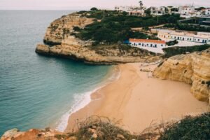 A stunning view of a sandy beach and cliffs in Algarve, Portugal, perfect for a relaxing vacation.