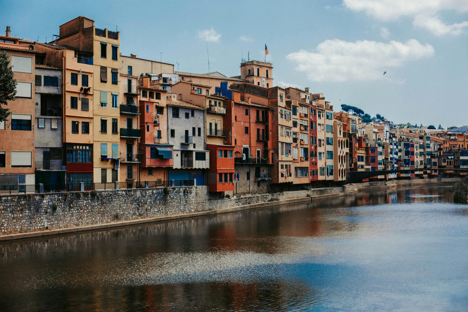 pexels-photo-9040187-9040187 Vibrant apartment facades line the Onyar River in Girona, Spain, reflecting architectural beauty.