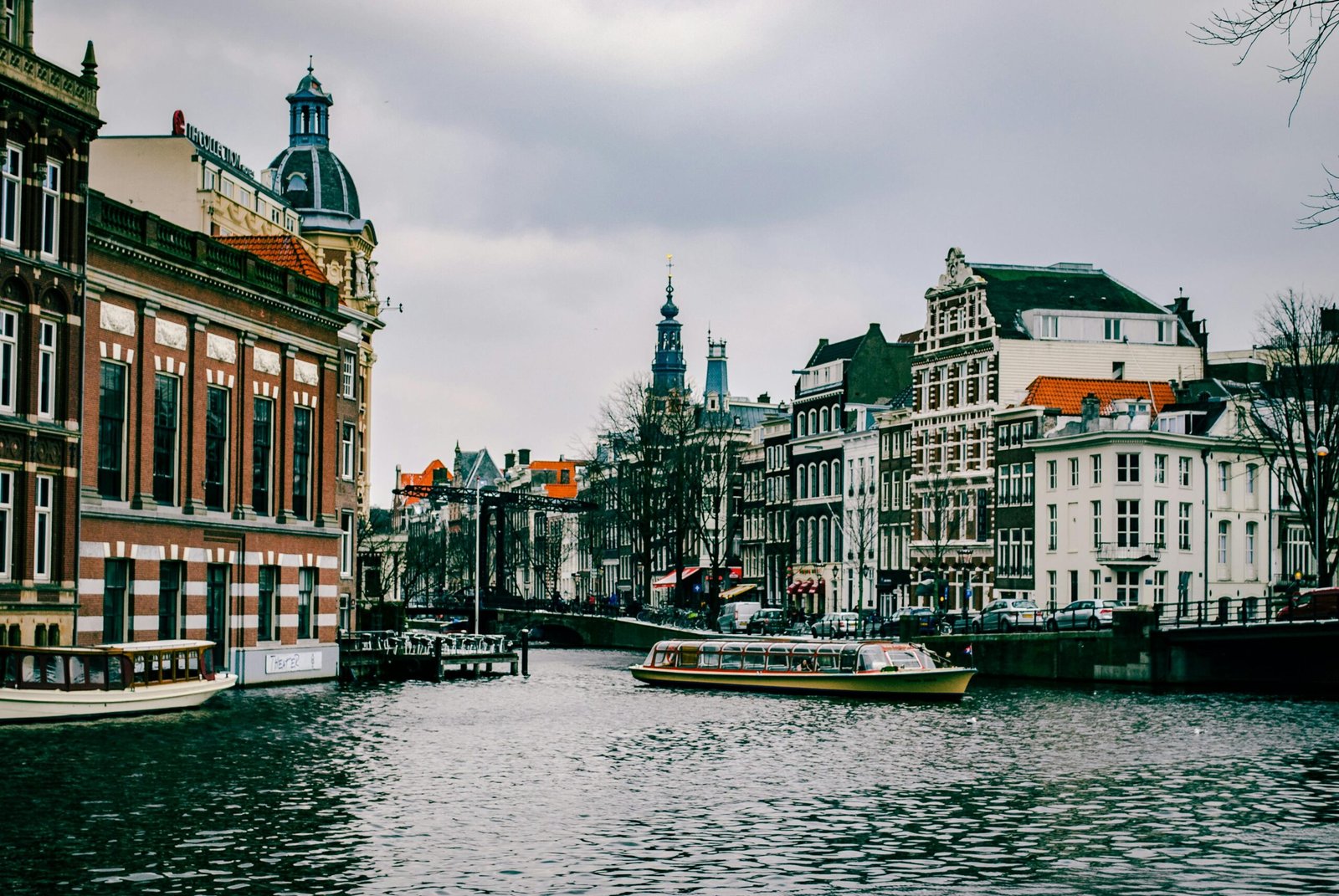 pexels-photo-967292-967292 Charming canal scene in Amsterdam with historic architecture and a passing boat.