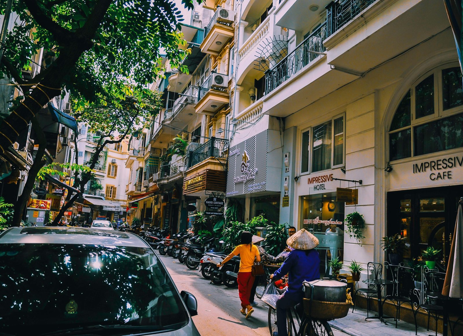 pexels-photo-1004122-1004122 Vibrant street life in Hanoi with locals, cafes, and motorbikes on a sunny day.