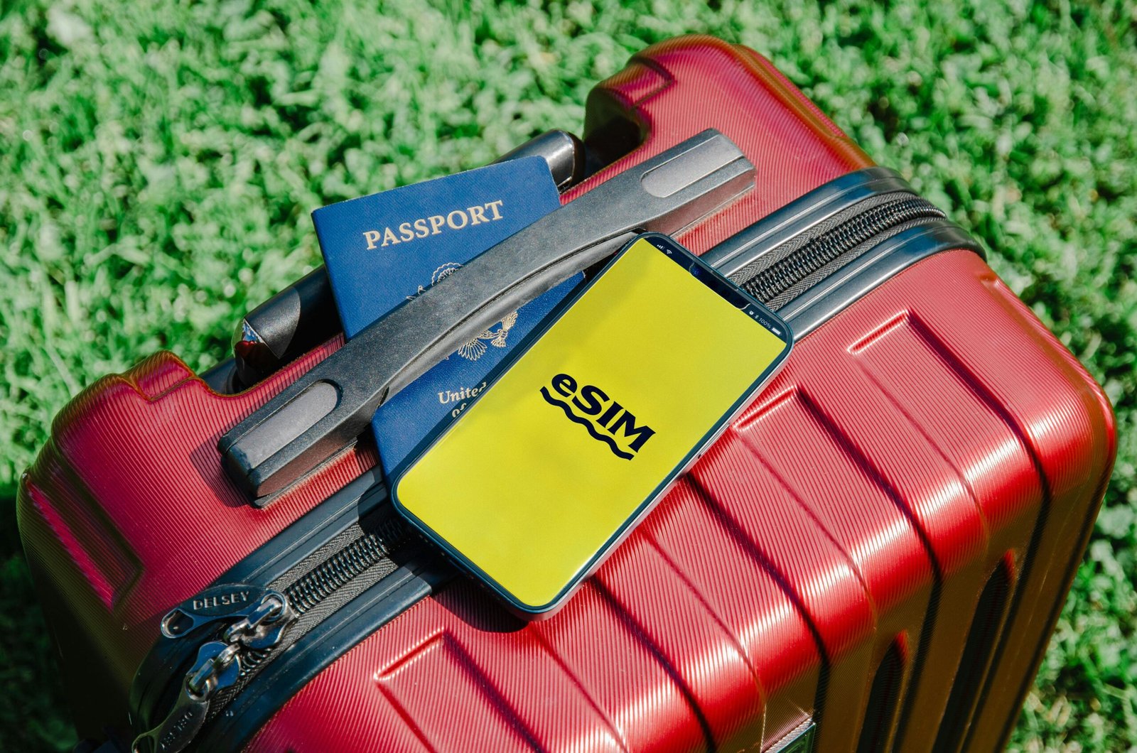 Close-up of a red suitcase with a smartphone displaying eSIM and a passport, symbolizing travel readiness.