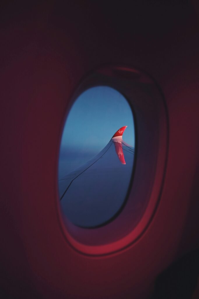 View of an airplane wing and sky from inside the cabin, creating a serene travel atmosphere.