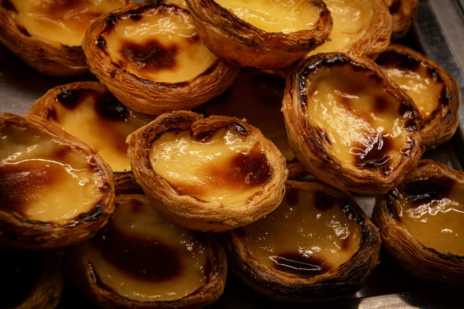 pexels-photo-2573870-2573870 A tempting display of traditional Portuguese Pastel de Nata pastries, glistening with caramelized tops.