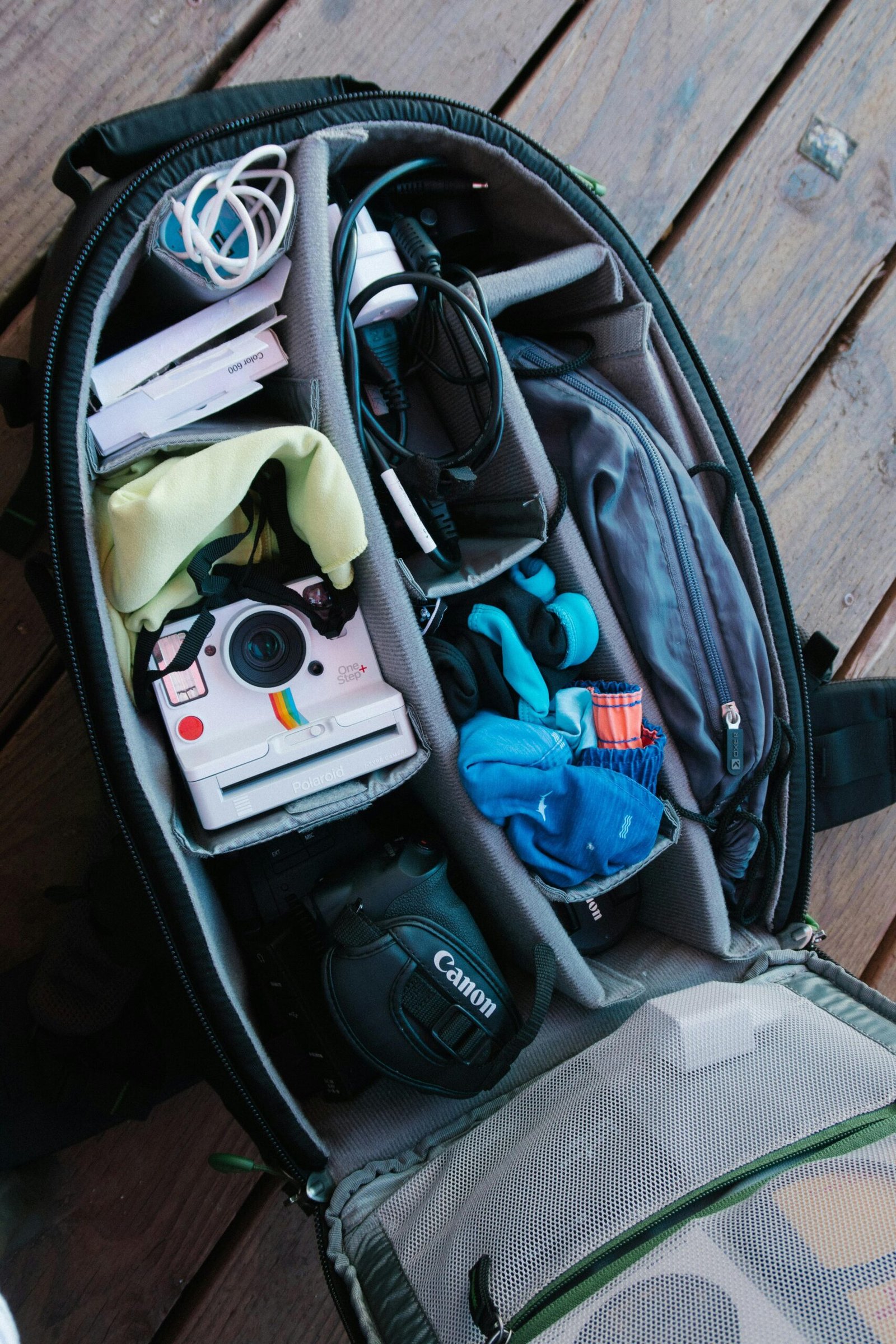 pexels-photo-2962099-2962099 Close-up of an open backpack filled with photography equipment on a wooden floor.