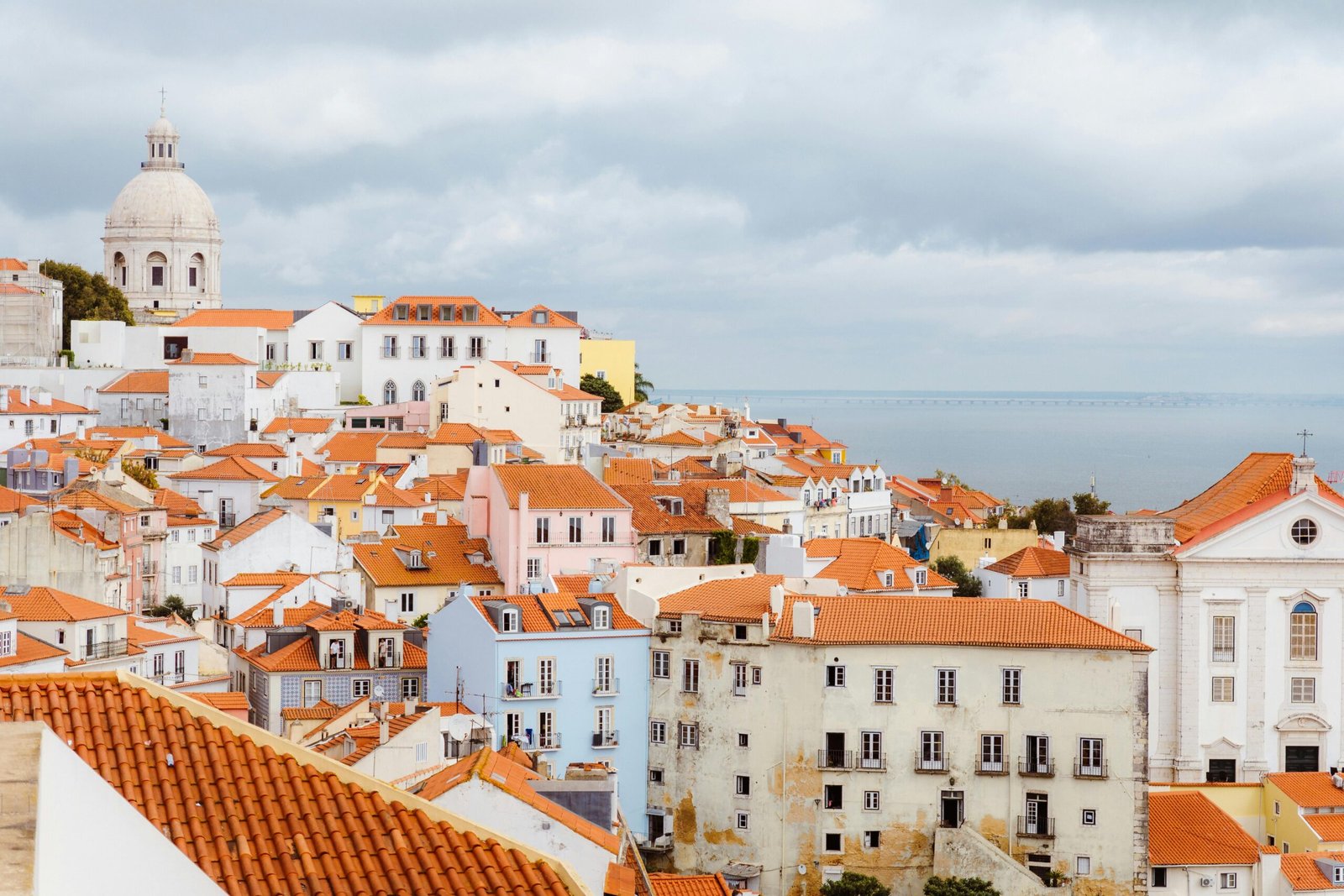 pexels-photo-29743107-29743107 Beautiful panoramic view of Lisbon's Alfama district with red rooftops and the sea in the background.