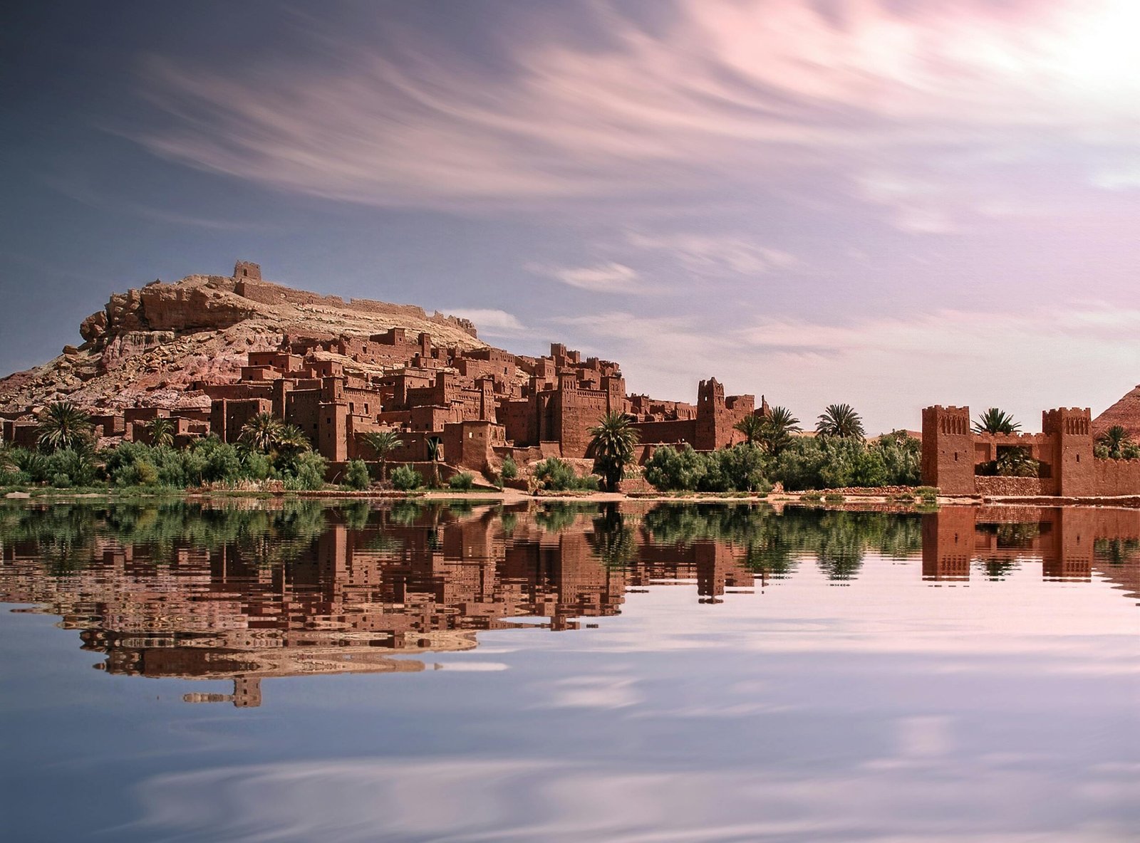 pexels-photo-3581916-3581916 Picturesque reflection of Ouarzazate's historic ksar by the river under a vibrant sky.