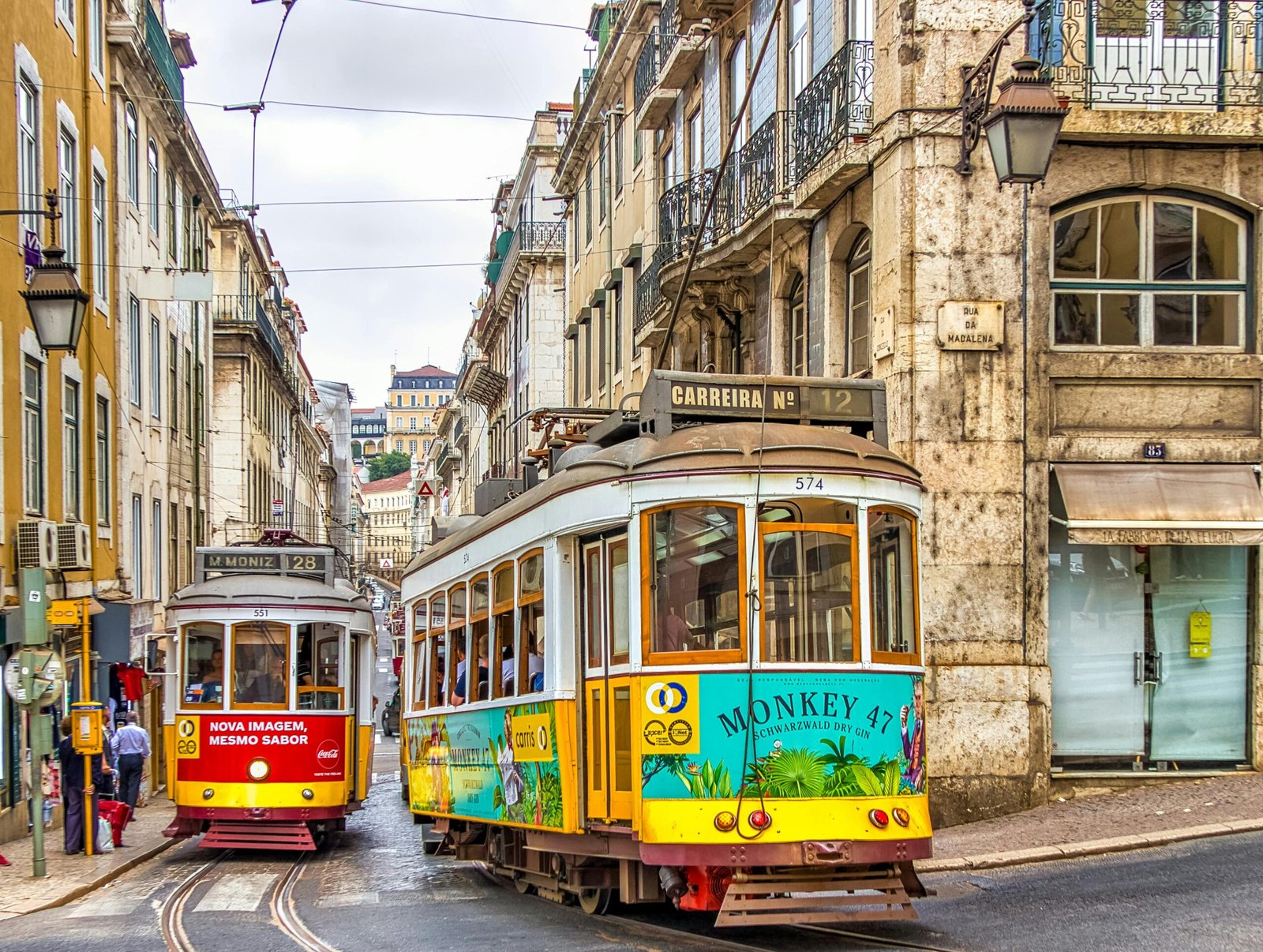 pexels-photo-3763903-3763903 Colorful trams on a vibrant street in Lisbon, showcasing historic architecture and urban life.