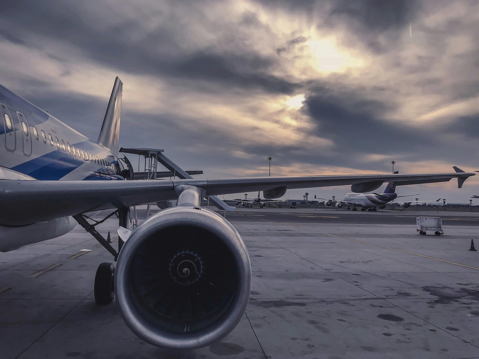 pexels-photo-912050-912050 A passenger airplane is parked on the tarmac at sunset, with another aircraft in the background.