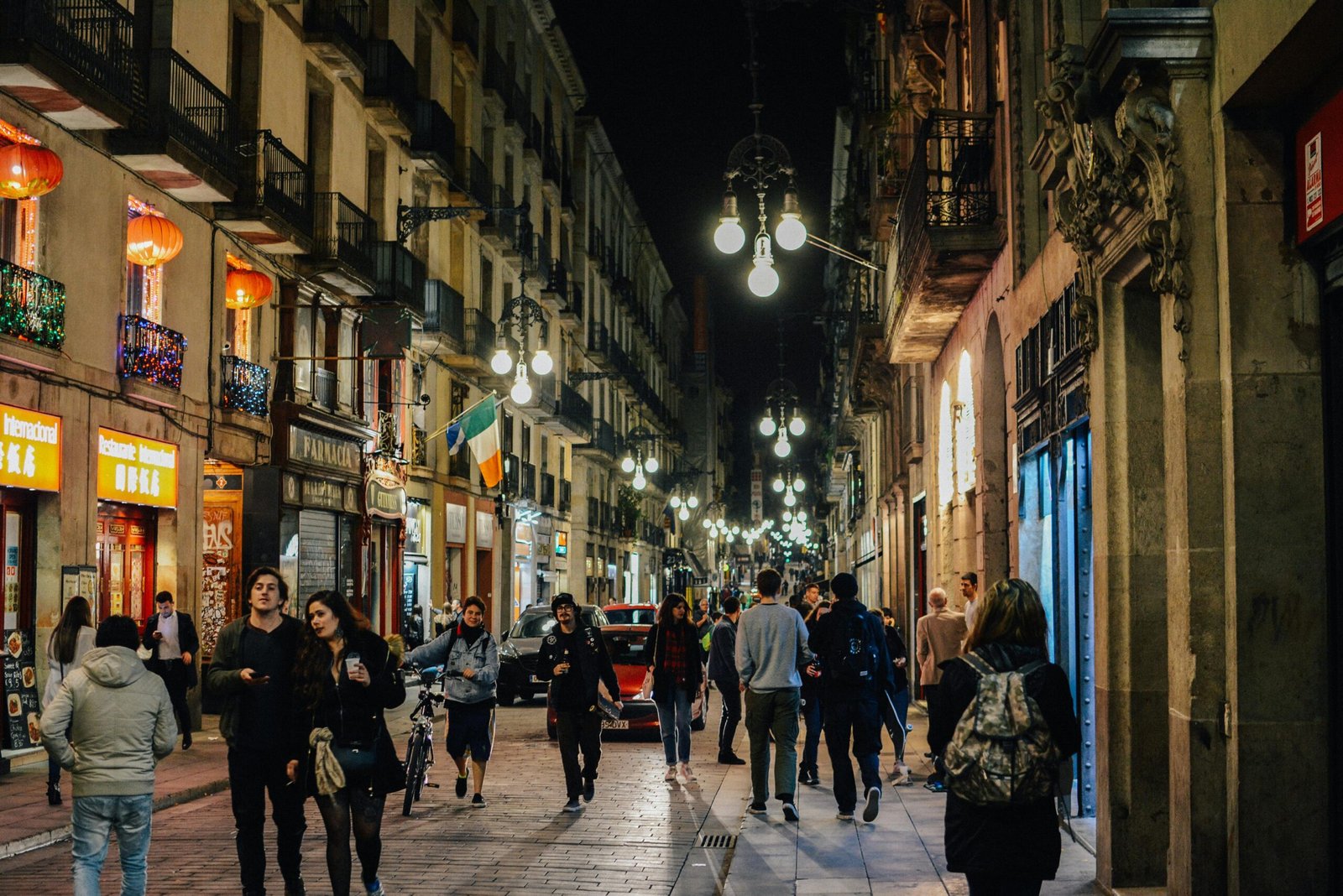 pexels-photo-1383779-1383779 Vibrant nightlife in Barcelona's old town with people walking under street lamps.