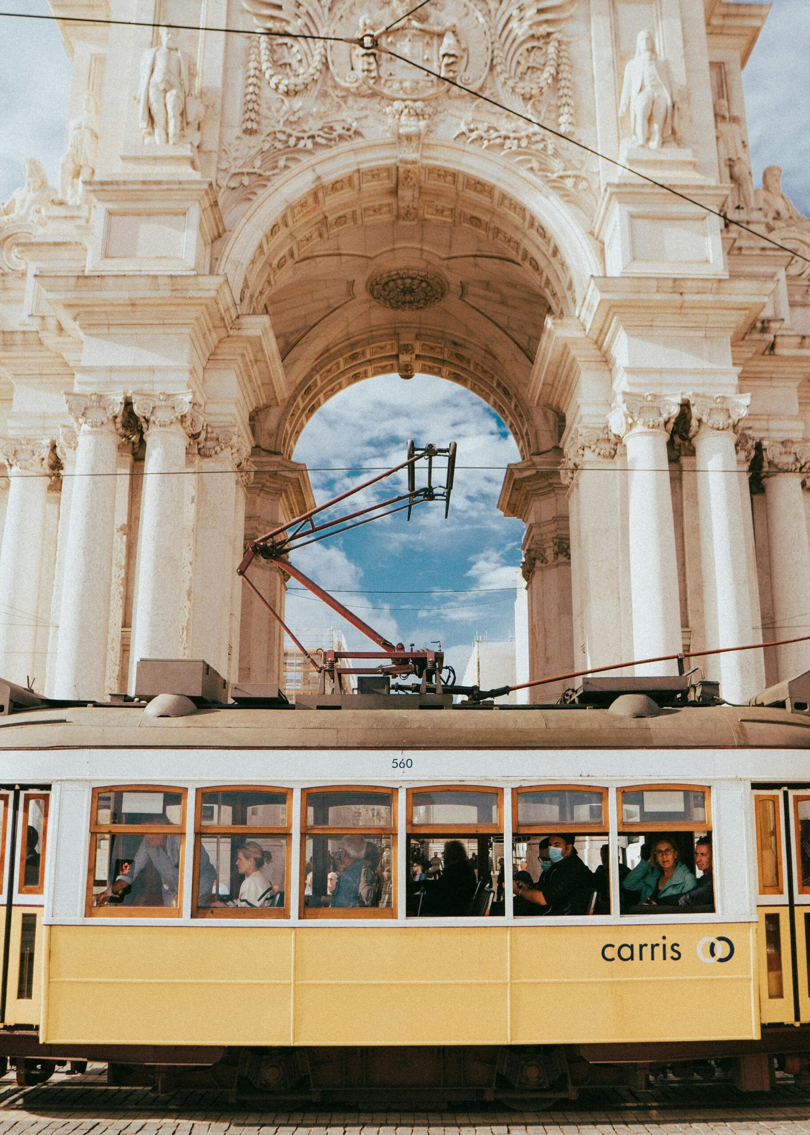 pexels-photo-14678583-14678583 Classic Lisbon tram passing beneath the historic Rua Augusta Arch, a symbol of Portuguese architecture.