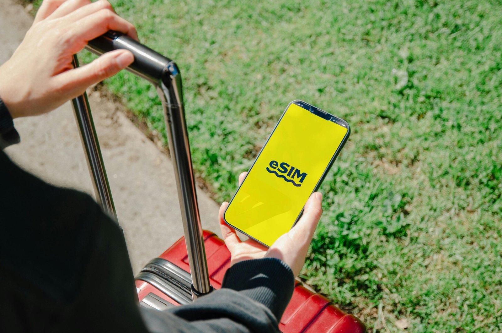 pexels-photo-20805599-20805599 A person holds a smartphone showing an eSIM app while standing with luggage outdoors in Los Angeles.