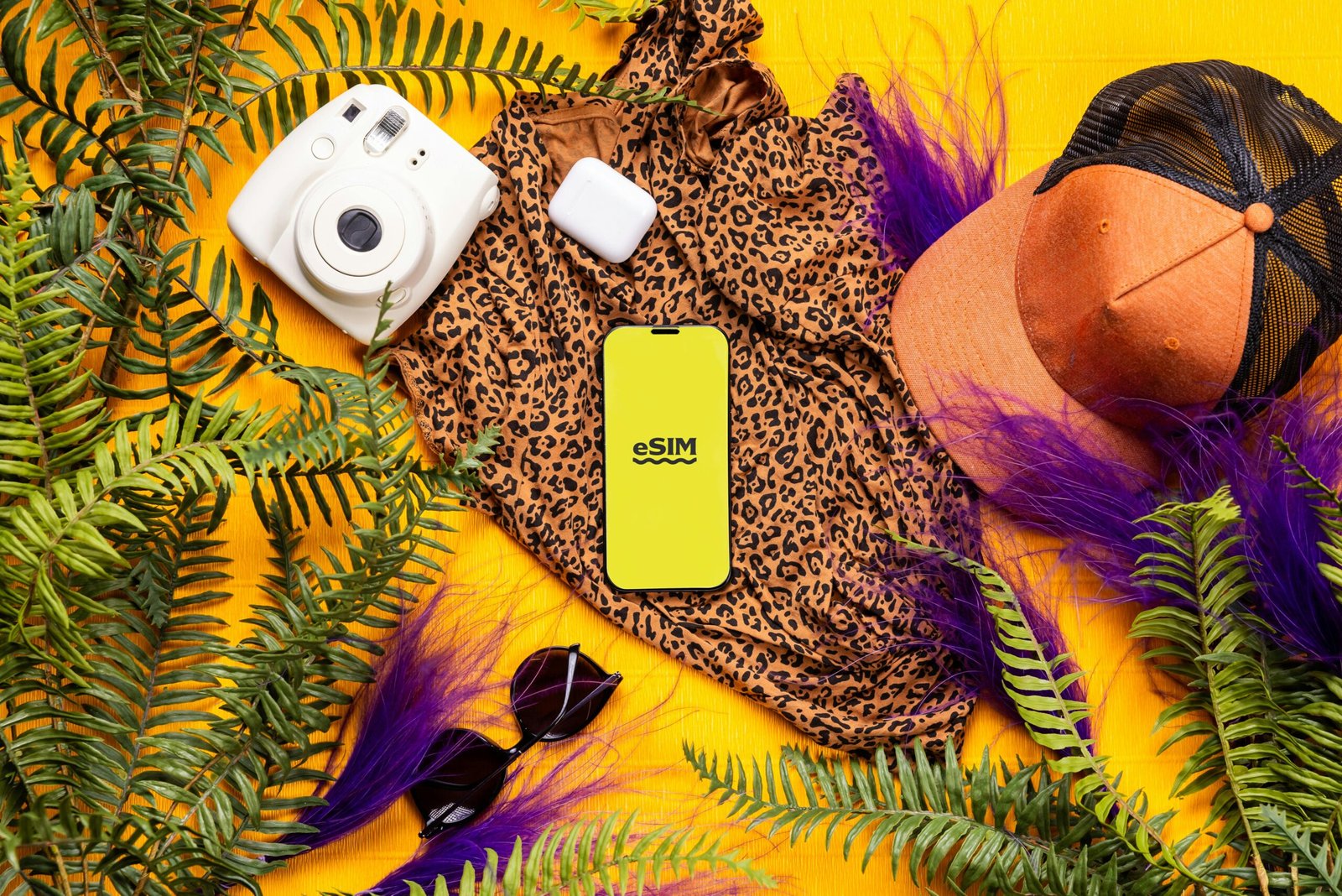 pexels-photo-26559665-26559665 Flat lay of summer travel essentials featuring a leopard print dress, gadgets, and greenery on a bright yellow background.