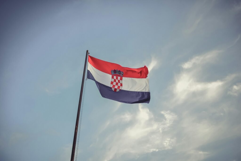 The Croatian flag blowing in the wind against a clear blue sky, symbolizing national pride.