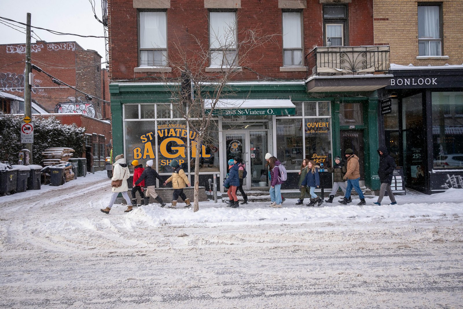 pexels-photo-30529087-30529087 A snowy street scene with pedestrians outside St Viateur Bagel Shop in Montréal.