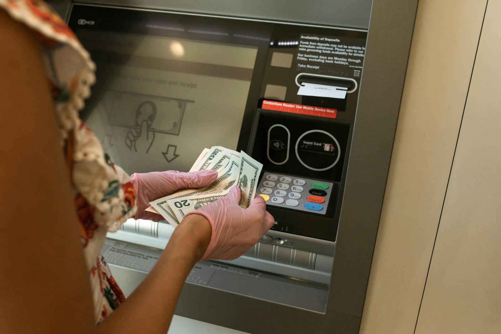 pexels-photo-5699376-5699376 A person wearing gloves withdraws cash from an ATM, ensuring hygiene.