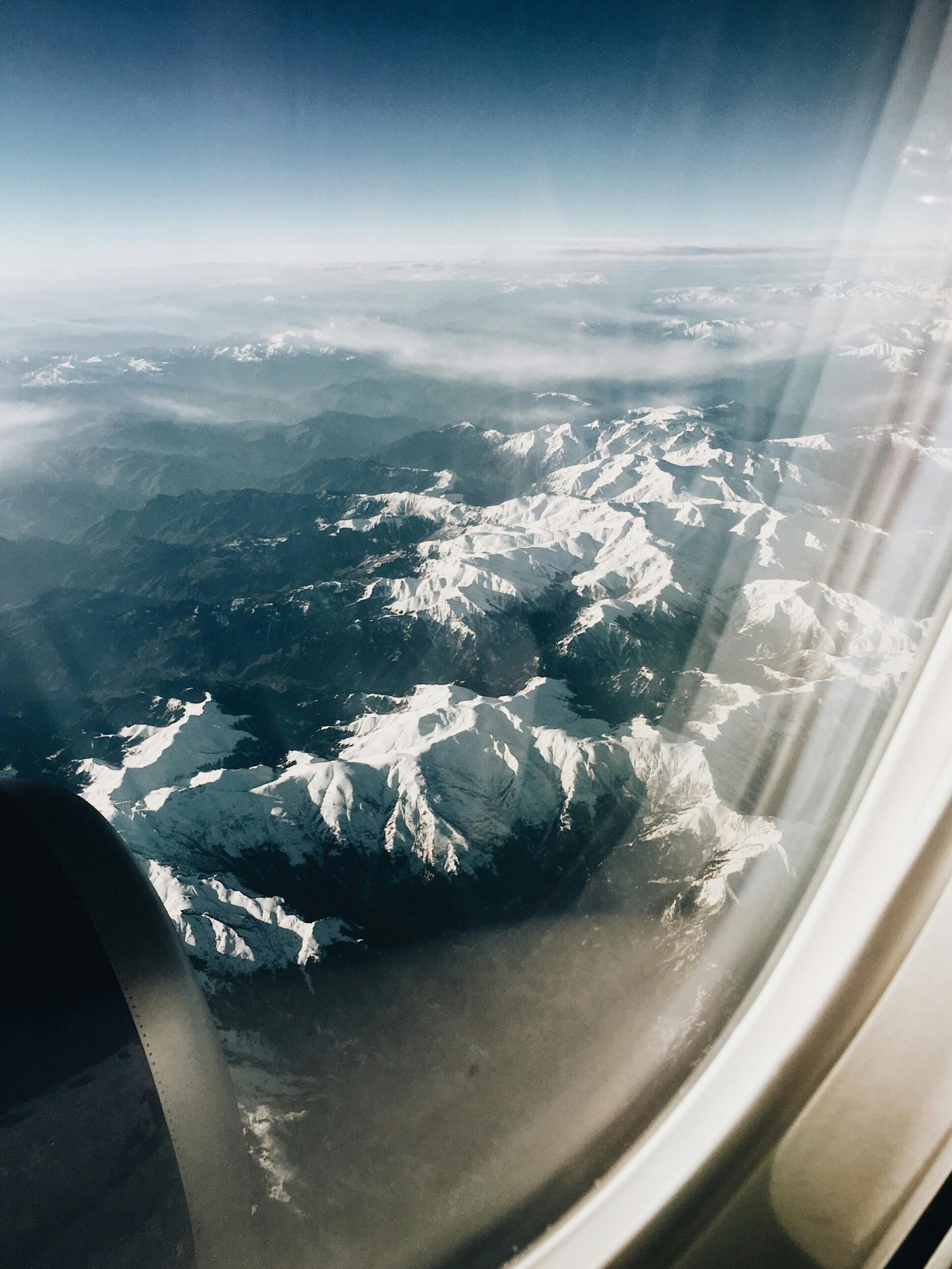 pexels-photo-8172320-8172320 Breathtaking aerial view of majestic snow-capped mountains through an airplane window.
