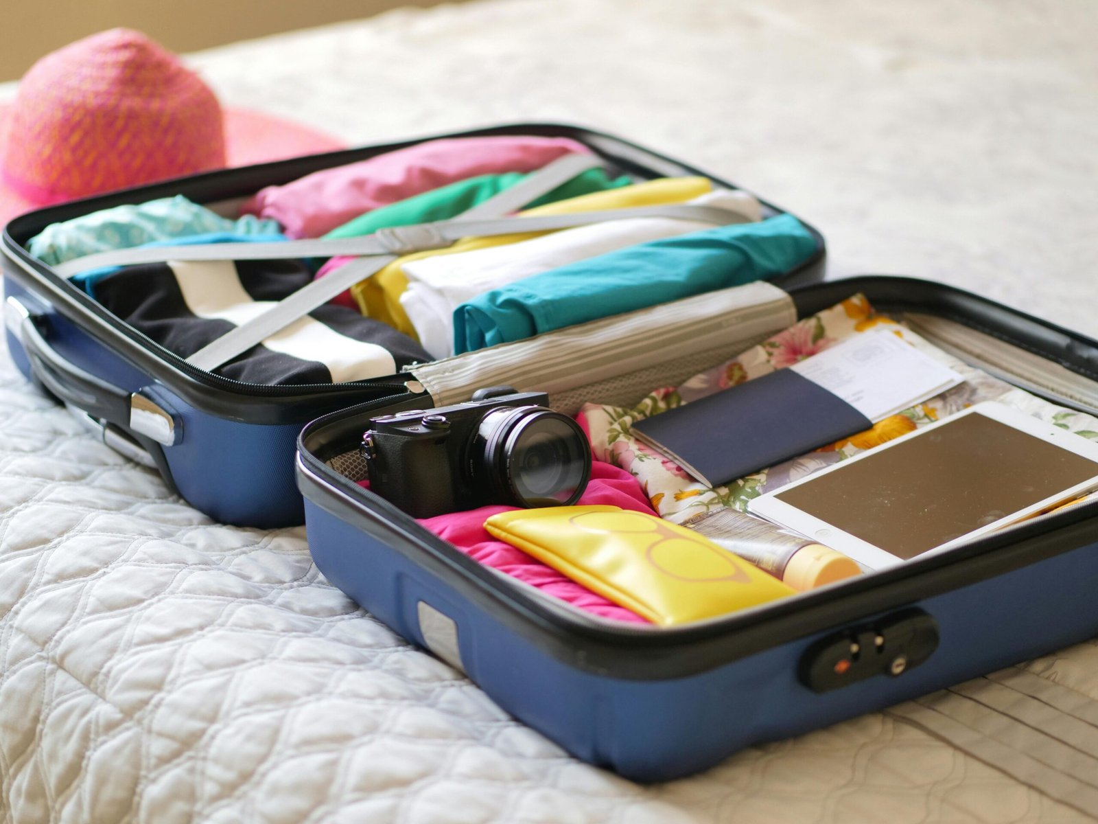pexels-photo-8212224-8212224 Open suitcase with camera, clothes, and passport, ready for a summer vacation.