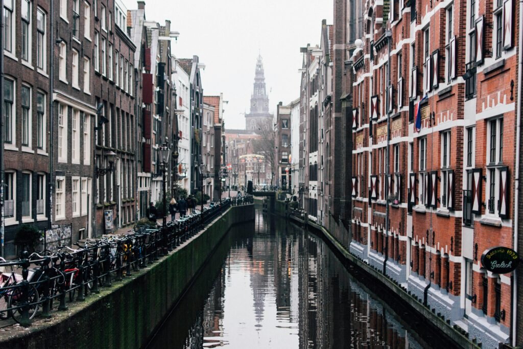 Misty view of a canal with bicycles and historic buildings in Amsterdam.