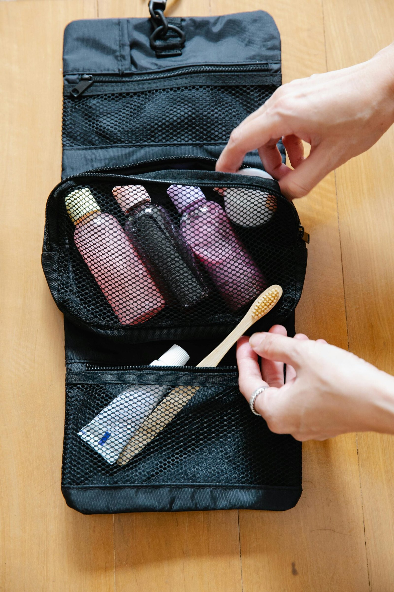 pexels-photo-9185864-9185864 Open toiletry bag with bottles and a bamboo toothbrush on wooden surface.