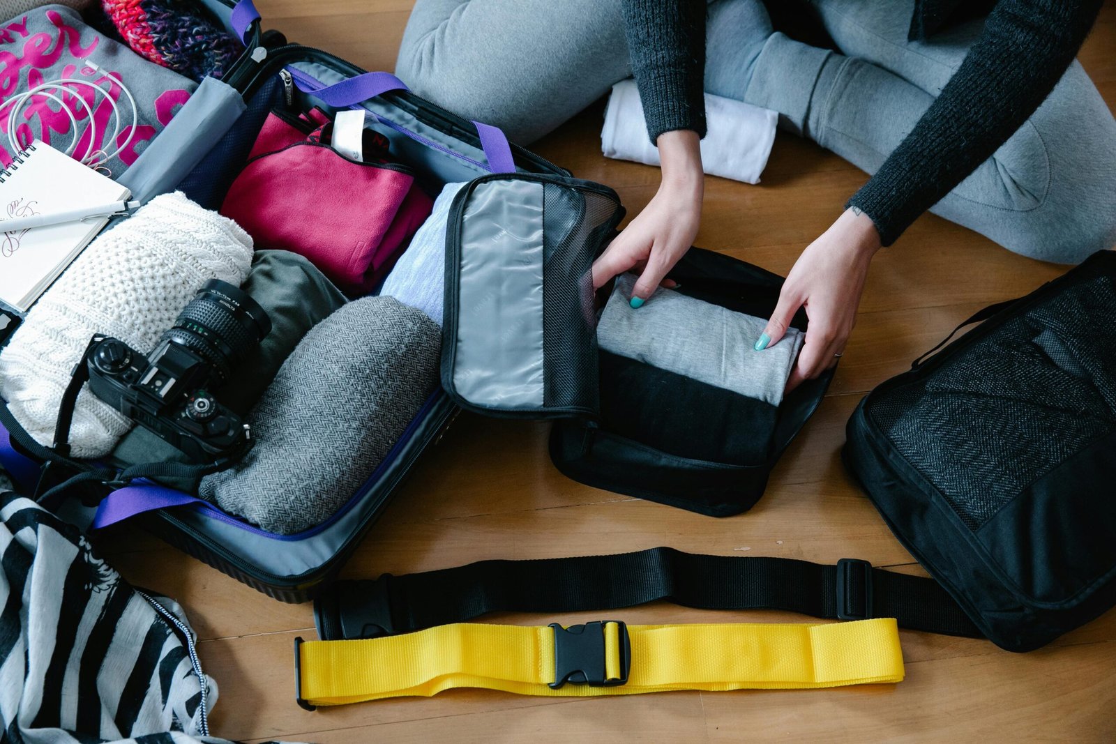 pexels-photo-9185880-9185880 A woman arranging clothes and accessories into a suitcase, preparing for travel.