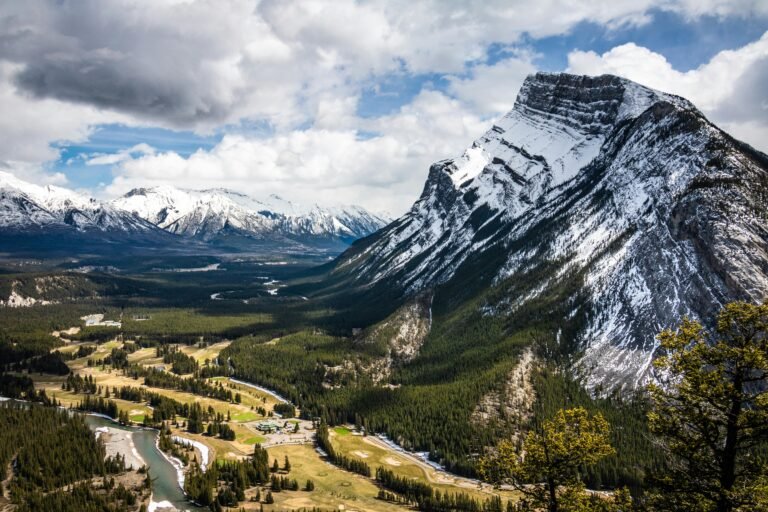 Breathtaking view of snow-capped mountains and lush valley in Banff National Park, perfect for nature enthusiasts.