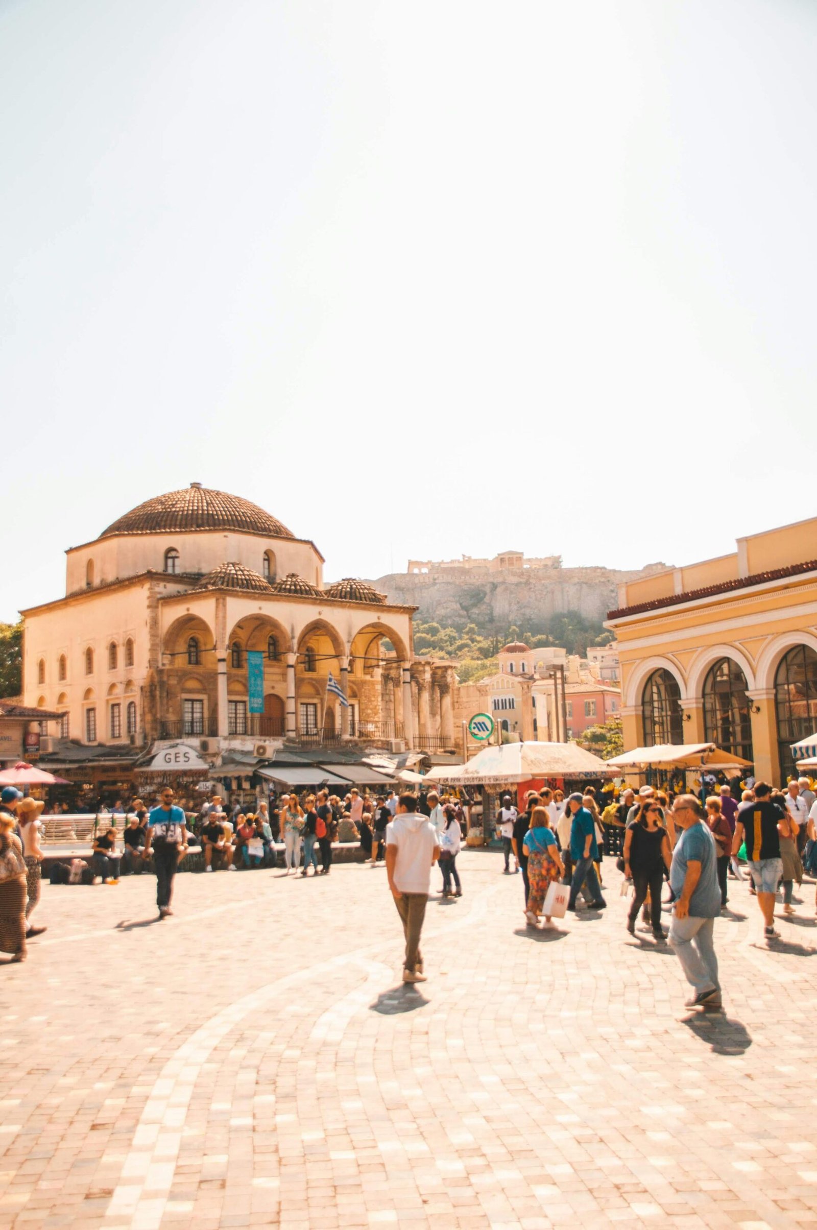 Lively scene at Monastiraki Square in Athens with people enjoying a sunny day, historic architecture in view.