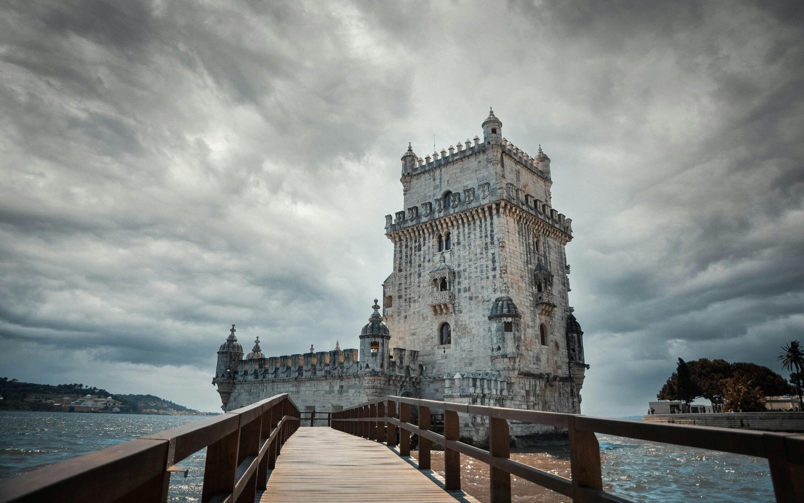 The iconic Belem Tower stands majestically over the Tagus River in Lisbon, Portugal under a dramatic sky.